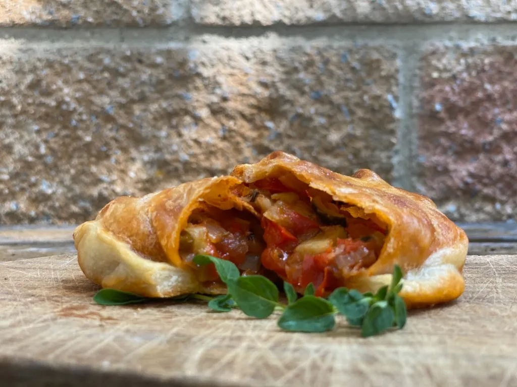 Gemüse-Empanada, goldbraun gebacken und mit Repulgue verschlossen