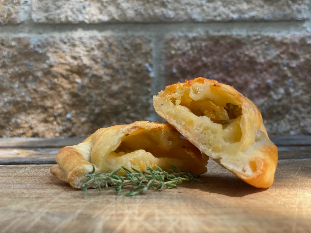 Käse-Empanada, goldbraun gebacken und mit Repulgue verschlossen